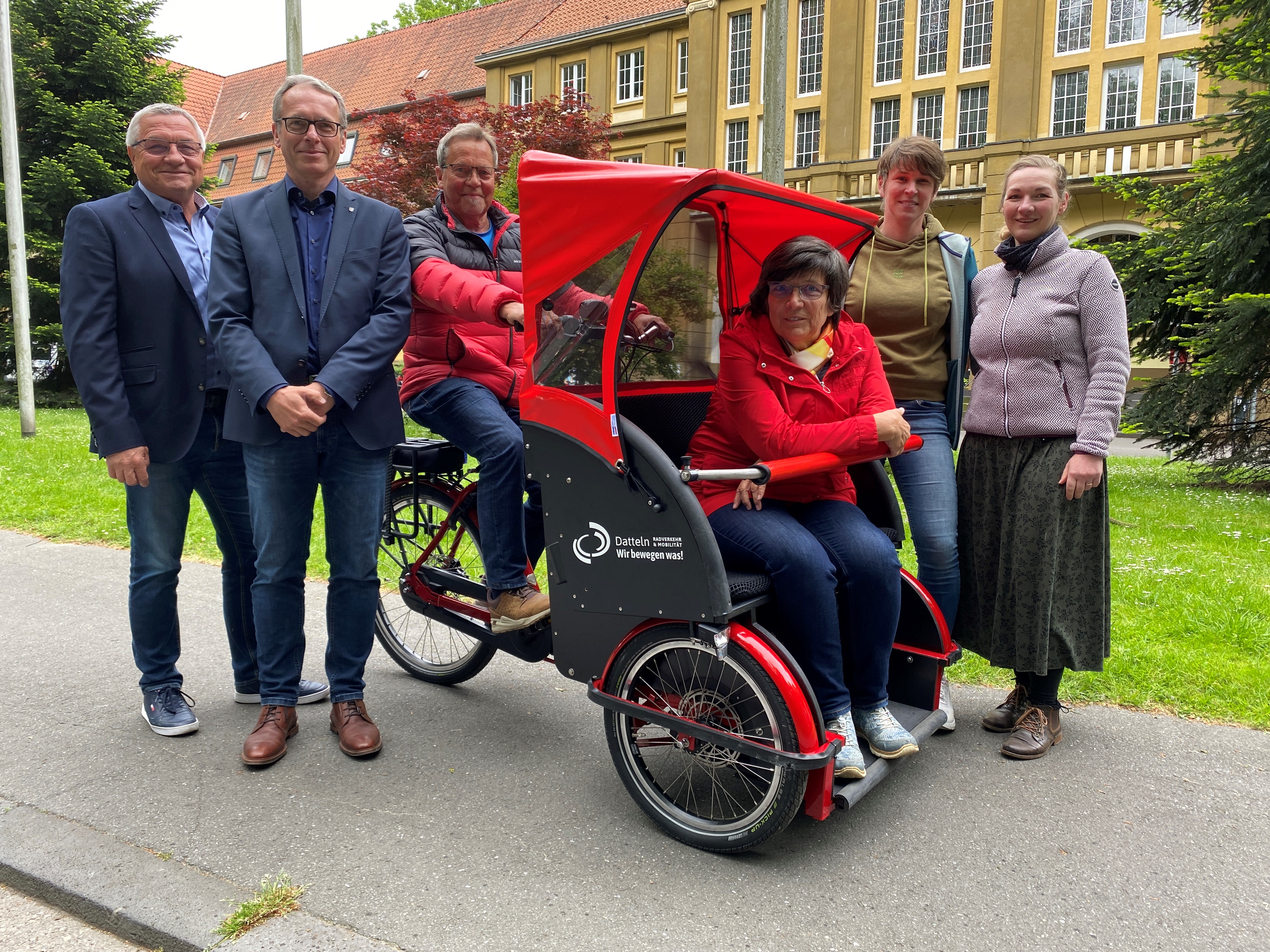 Eine Fahrradrikscha und folgende Personen (v. l.): Klaus Herrmann (Seniorenbeirat), Bürgermeister André Dora, Herbert Wenner (Seniorenbeirat) und Margarete Kelch (Vorsitzende des Seniorenbeirats), Radverkehrsbeauftragte und Mobilitätsmanagerin Anja Althoff und Klimaschutzmanagerin Stefanie Pfitzmann.