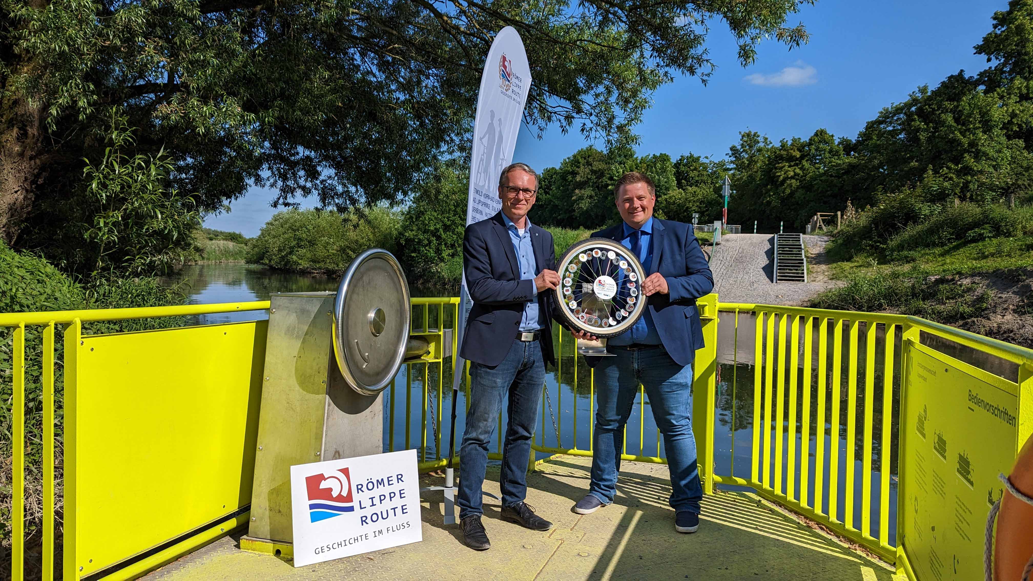 Dattelns Bürgermeister André Dora (links) übergibt das Römer-Lippe-Routen-Rad an Halterns Bürgermeister Andreas  Stegemann.