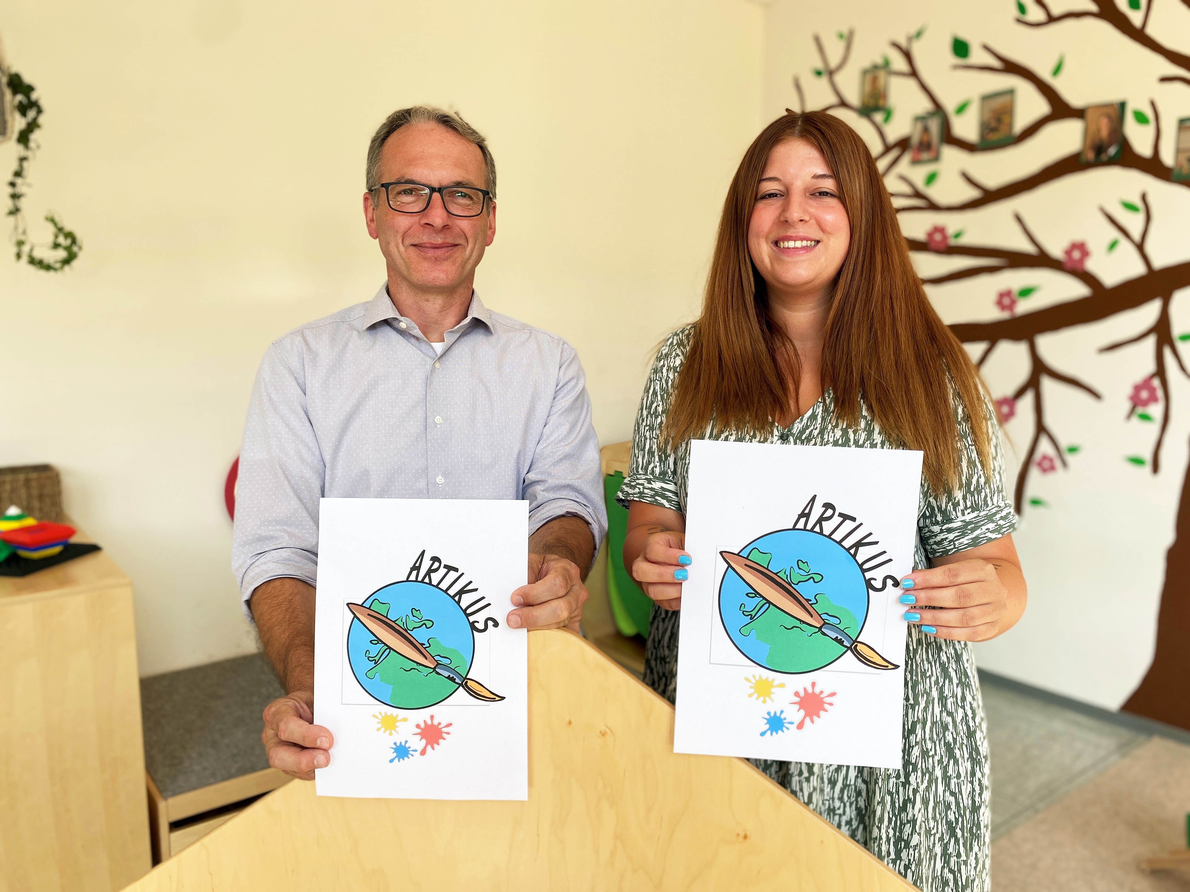 Bürgermeister André Dora und Kita-Leiterin Kim Starschinski zeigen das neue Logo des Kindertagestageseinrichtung ARTIKUS
