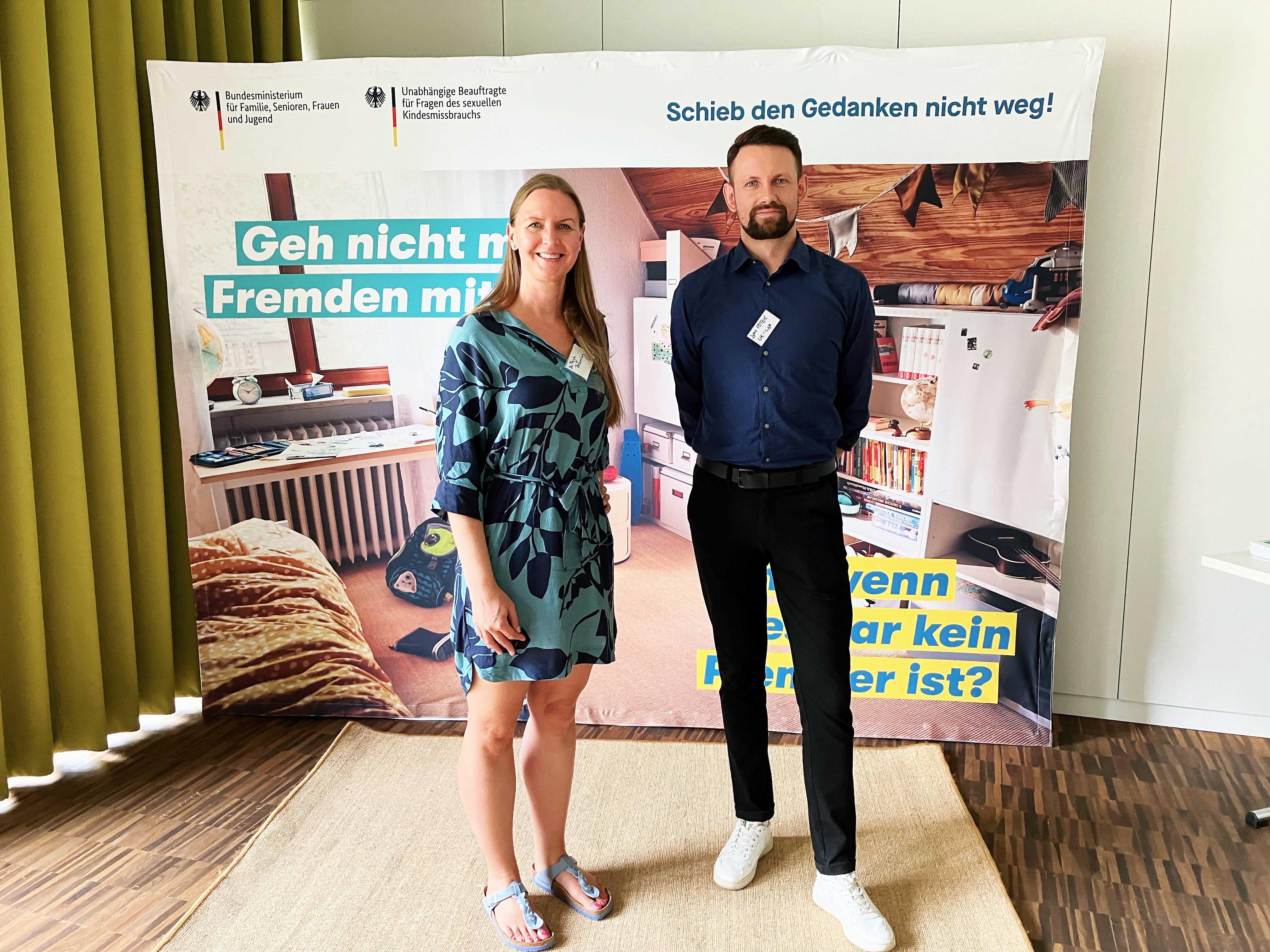 Dr. Tanja Brüning und Jan Pöter stehen im Amandusforum vor einem Plakat zum Thema Kinderschutz.