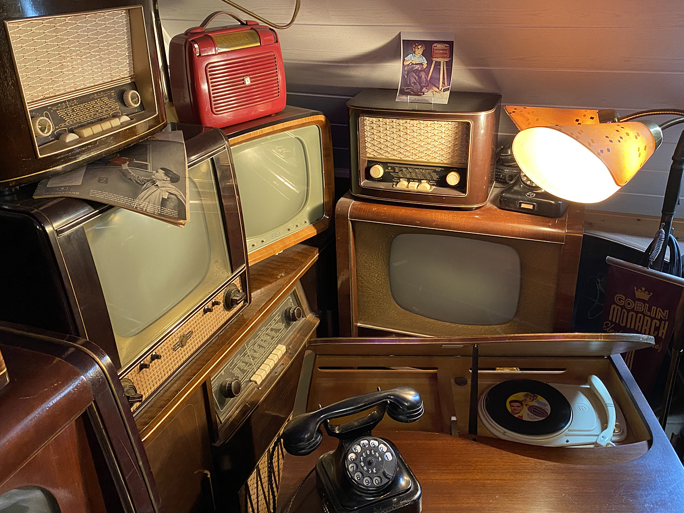 Historische Rado- und Fernsehgeräte, eine alte Lampe und ein Wählscheibentelefon.