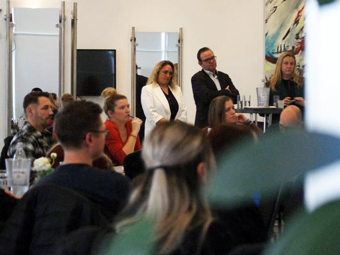 Mehrere Personen lauschen - entweder stehend oder sitzend - einem Vortrag in der Oer-Erkenschwicker Stadthalle