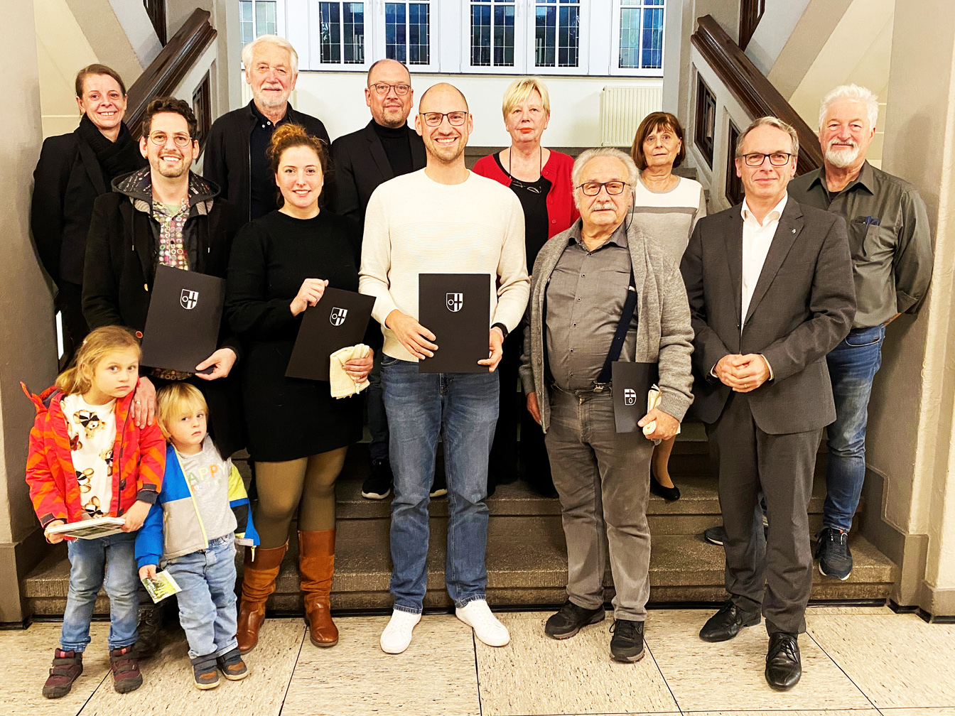 Das Foto zeigt von links auf der Treppe im Rathaus folgende Erwachsene: Umweltbeauftragte Jasmin König, Lars Pompös, Theodor Beckmann (WV Die Grünen), Melanie Bleicher, Falco Böhlje, Keven Hebekeuser, Petra Willemsen (DIE LINKE), Günter Jordan, Gabriele Weigand (UBP), Bürgermeister André Dora und Joachim Lehmann (SPD).