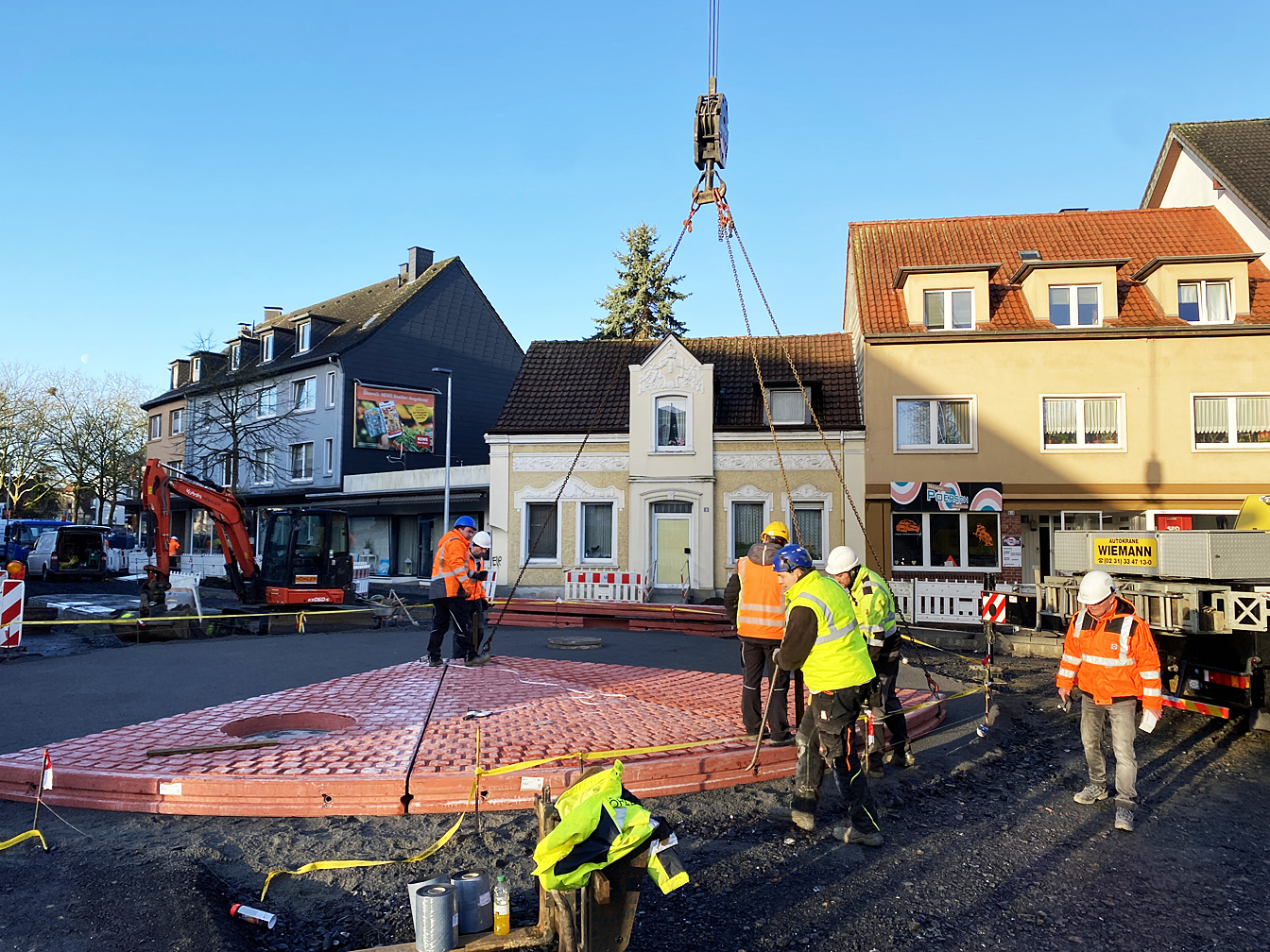 Arbeiter verlegen Betonelemente für den neuen Kreisverkehr an der Hafenstraße. 
