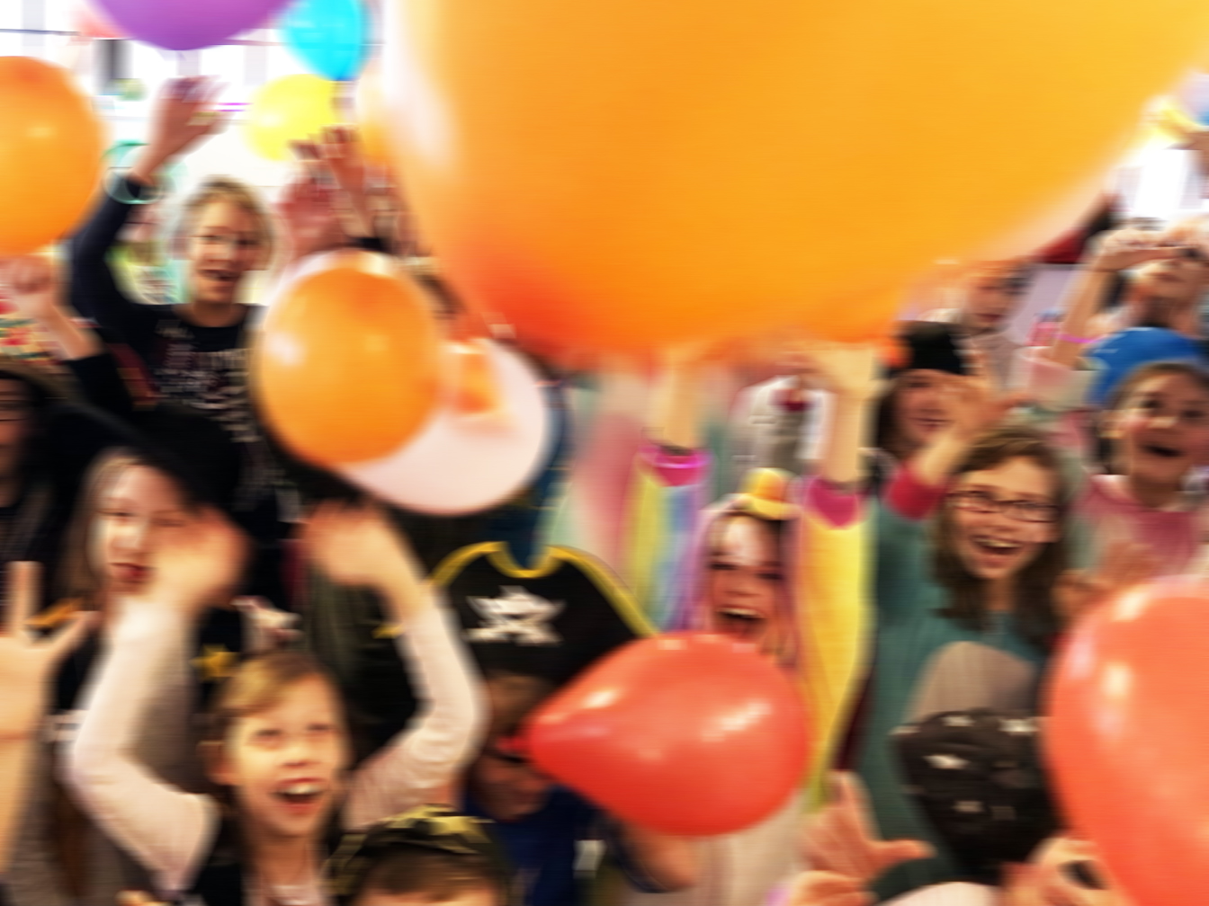 Kostümierte Kinder, die mit Luftballons spielen und Karneval feiern