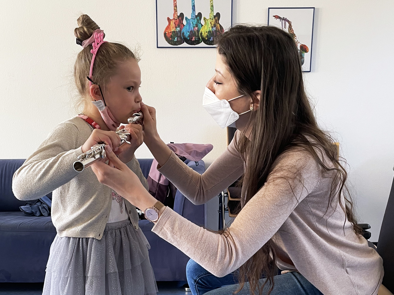 Eine Musikschullehrerin erklärt einem Mädchen, wie man auf der Querflöte spielt.