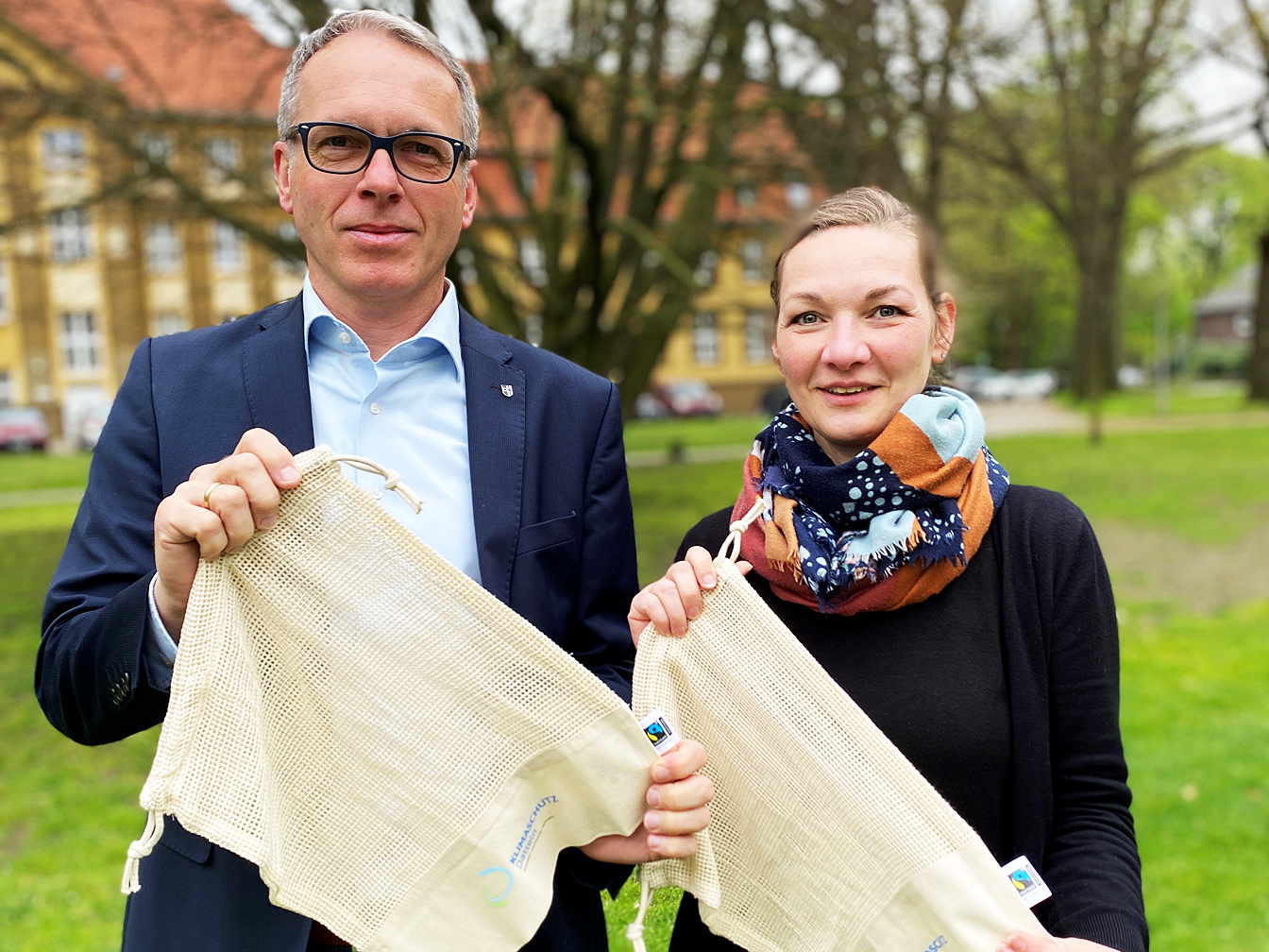 Bürgermeister André Dora und Klimaschutzmanagerin Stefanie Pfitzmann zeigen vor dem Rathaus Fairtrade-Mehrwegnetze.
