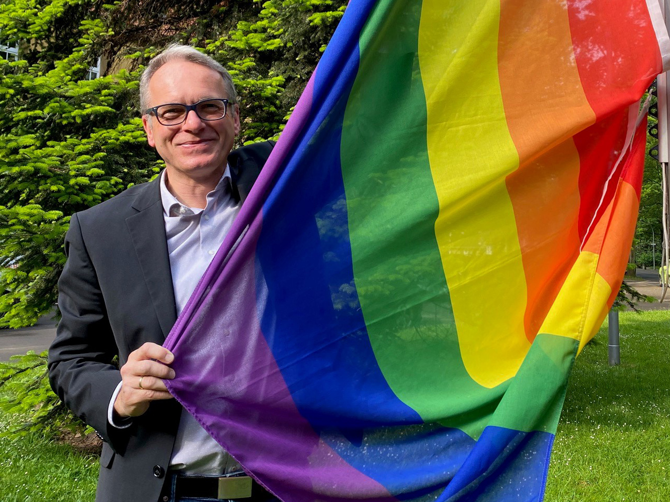 Bürgermeister André Dora mit Regenbogenfahne am Rathaus