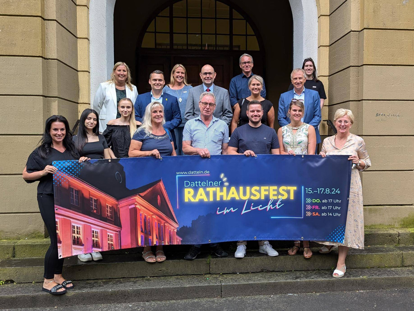 Sponsor*innen und Rathaus-Mitarbeiter*innen mit dem Bürgermeister am Rathausportal, um das Programm für das Rathausfest 2024 vorzustellen.