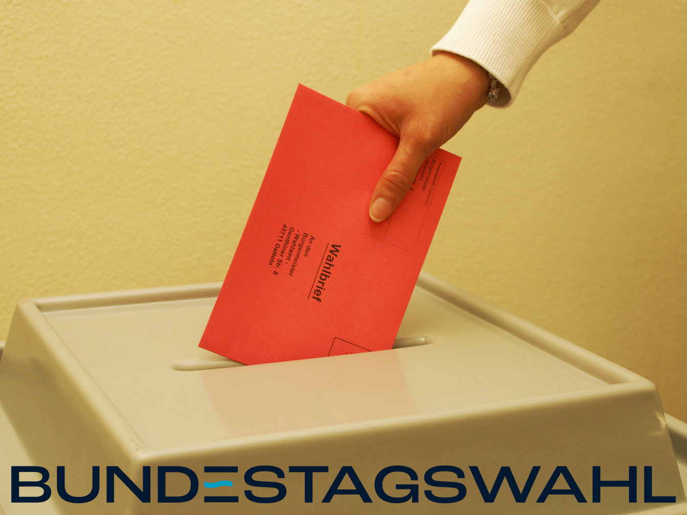 Wahlbrief wird in eine Wahlurne gesteckt.