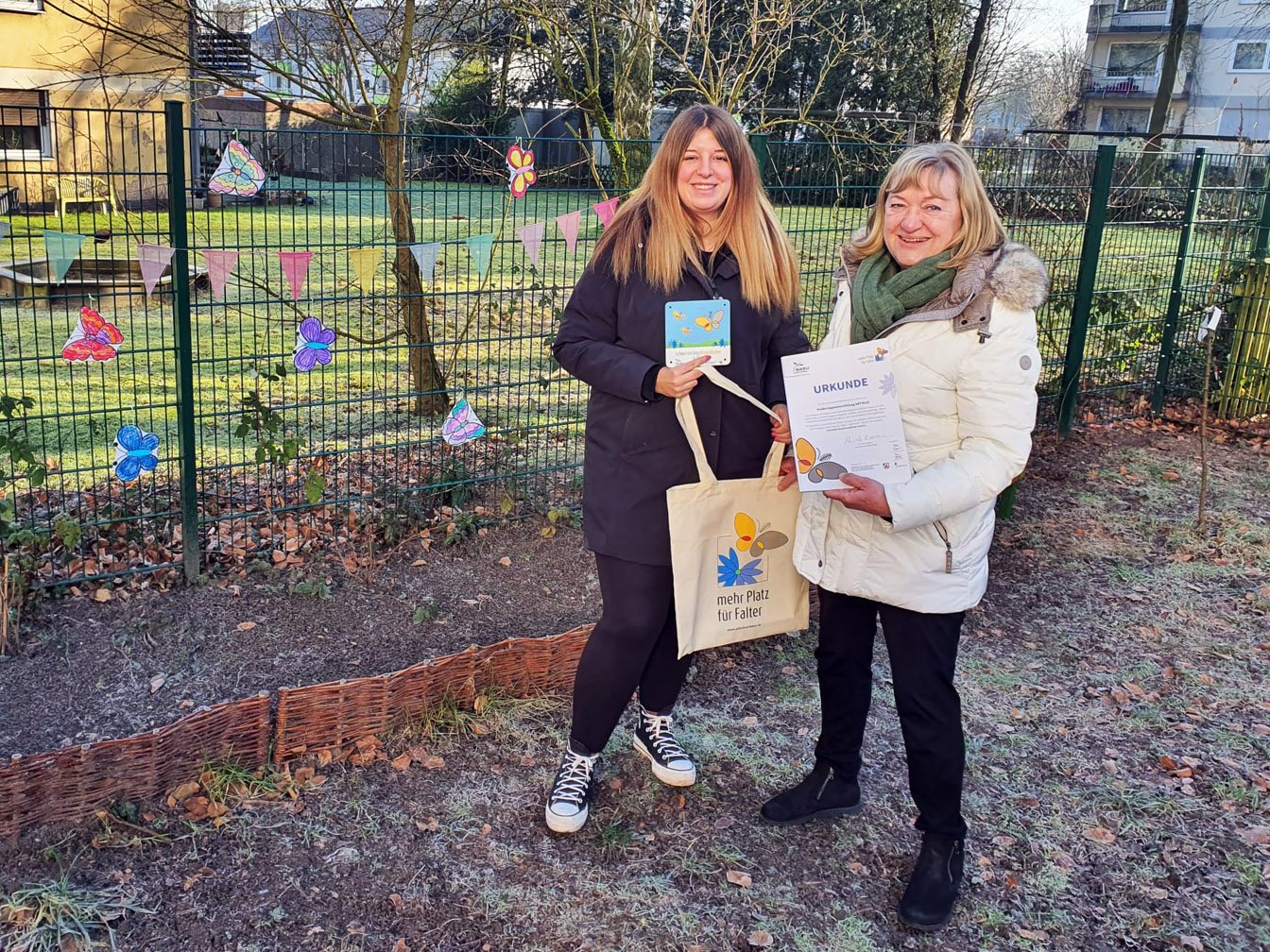 Kim Starschinski (l.), Leiterin des Familienzentrums ARTIKUS, erhält von Marita Eckart vom Nabu die Urkunde "Schmetterlingsfreundlicher Garten" für ihre Einrichtung
