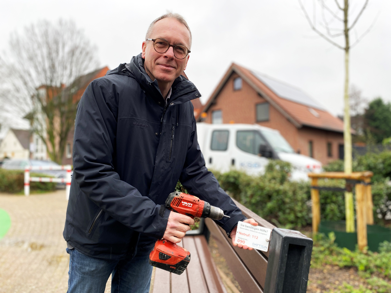 Bürgermeister André Dora zeigt das Schild mit der Nummer, das an die Bänke angebracht wird.