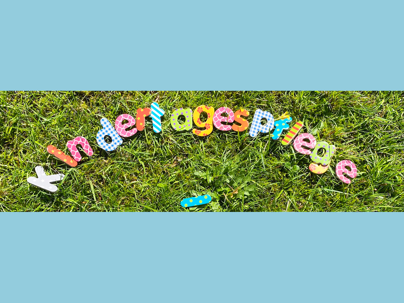 Bunte Buchstaben auf einer Wiese, die das Wort "Kindertagespflege" bilden