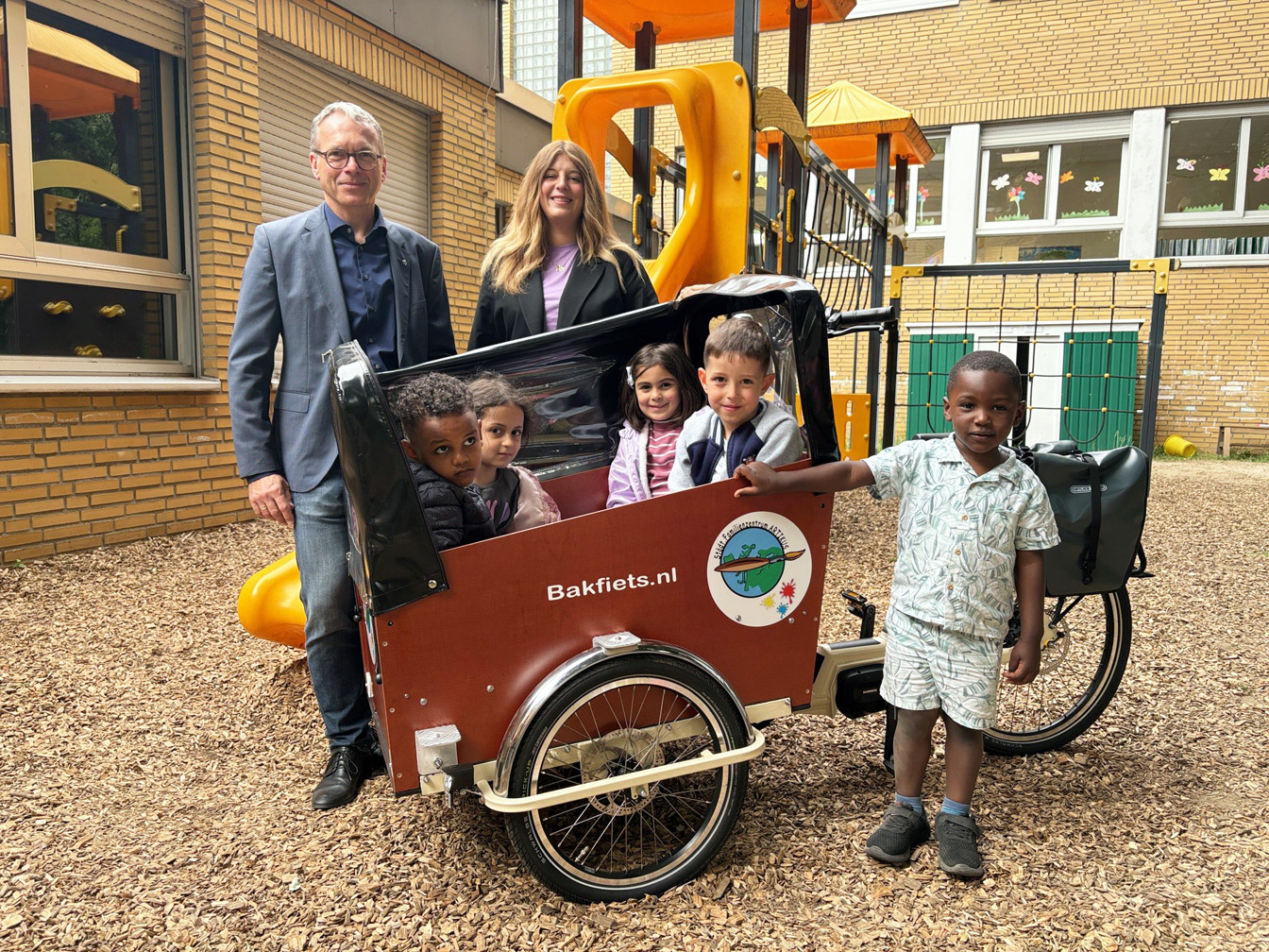 Das Foto zeigt Bürgermeister André Dora und Kita-Leiterin Kim Starschinski am Lastenrad und fünf Kinder des Familienzentrums ARTIKUS