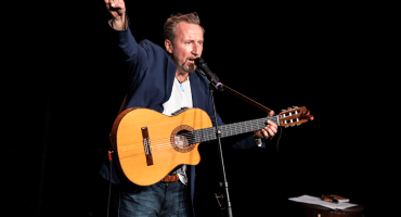 Helmut Sanftenschneider mit Gitarre auf einer Bühne.