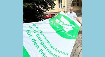 Bürgermeister André Dora mit der "Mayors for Peace"-Flagge vor dem Rathaus.