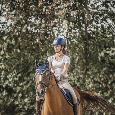 Das Bild zeigt eine Reiterin auf ihrem Pferd.