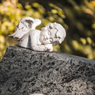 Das Bild zeigt einen Engel auf einem Grabstein.