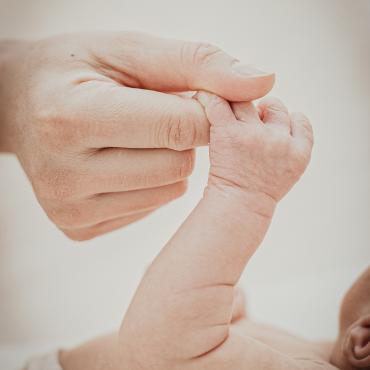 Das Bild zeigt die Hand eines Neugeborenen in einer erwachsenen Hand.