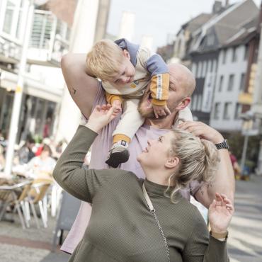Das Bild zeigt eine Familie in der Innenstadt. 