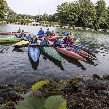Das Bild zeigt Kinder in Kanus.