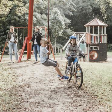 Das Bild zeigt zwei Jungs mit ihren Müttern auf einem Spielplatz.