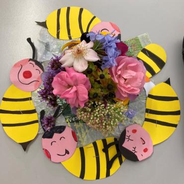 Das Bild zeigt bunte Blumen und Papierbienen.