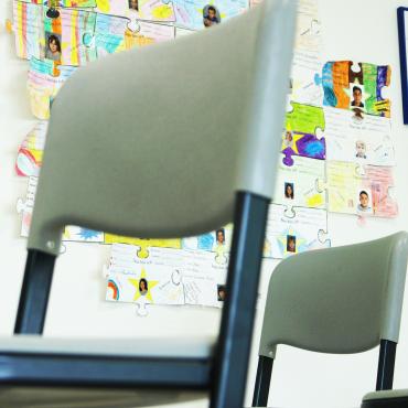 Das Bild zeigt hochgestellte Stühle in einer Schulklasse