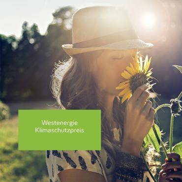 Frau, die an einer Sonnenblume riecht. Im Hintergrund geht die Sonne unter.