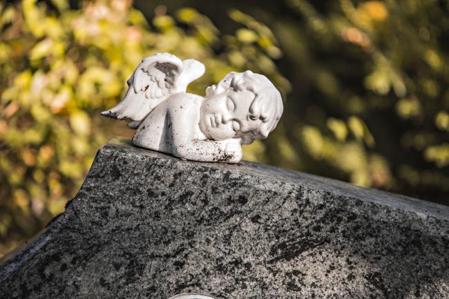 Das Bild zeigt einen Engel auf einem Grabstein.