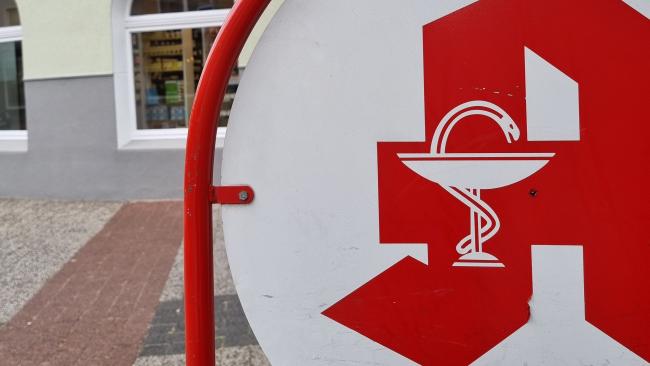 Das Bild zeigt ein Schild mit Apothekenzeichen.