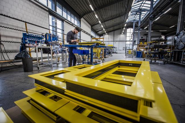 Das Bild zeigt eine Produktionshalle mit einem arbeitenden Menschen.