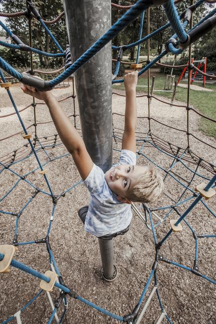 Das Bild zeigt einem auf dem Klettergerüst spielenden Jungen.