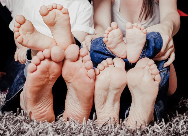 Das Bild zeigt die Füße von zwei Erwachsenen und zwei Kindern.