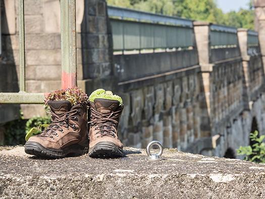 Das Bild zeigt Wanderschuhe auf einer Brücke.