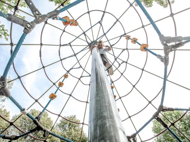Das Bild zeigt einen spielenden Jungen auf einem hohen Klettergerüst.