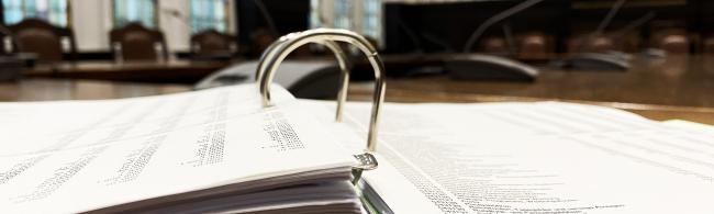 Das Bild zeigt einen aufgeschlagenen Ordner mit Haushaltsdaten im Sitzungssaal