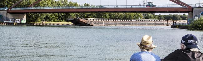 Das Wasser zeigt den alten Liegehafen, im Vordergrund sitzen zwei Personen.
