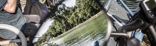 Das Bild zeigt Personen auf einer Bank und der Dortmund-Ems-Kanal, der sich in einem Spiegel spiegelt