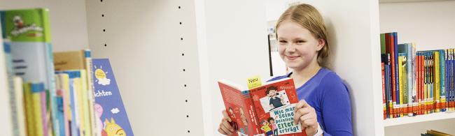 Das Bild zeigt ein Mädchen, das ein Buch in der Hand hält.