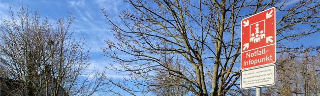 Das Bild zeigt ein rotes Schild, das auf einen Notfall-Infopunkt hinweist