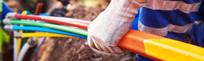 Das Bild zeigt einen Menschen, der verschiedenfarbige  Kabel in der Hand hält.