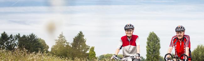 Das Bild zeigt zwei Senior*innen beim Fahrradfahren.