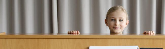 Das Bild zeigt ein Mädchen, das hinter einem Klavier steht.