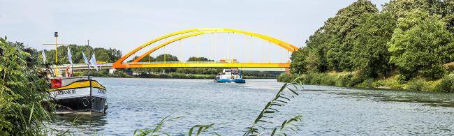 Das Bild zeigt das Dattelner Meer, auf der linken Seite ein Binnenschiff und im Hintergrund den Dattelner-Meer-Bogen.