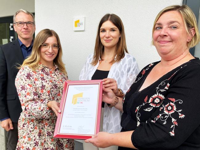 Das Foto zeigt von links Bürgermeister André Dora sowie die pädagogischen Fachkräfte der städtischen Kanello-Kita Melina Behrendt, Hannah Groß und Tanja Lücke, die das Zertifikat für das Familienzentrum zeigen.