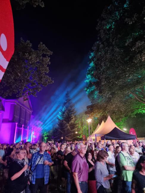 Zuschauerinnen und Zuschauer vor dem illuminierten Rathaus, die sich die Band auf der Bühne anschauen 