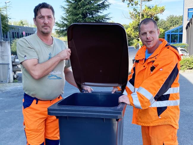 Christian Schulwandt (links) und Marcel Lissowski halten den Deckel einer Biotonne auf. 