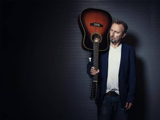 Helmut Sanftenschneider mit Hemd und Sakko und Gitarre in der Hand