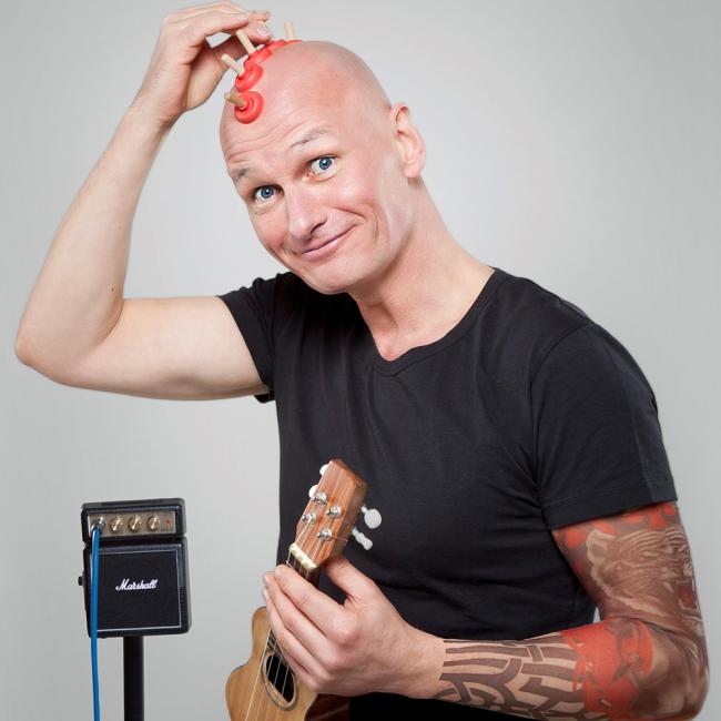 Klaus Renzel mit Mini-Gitarre in der Hand.